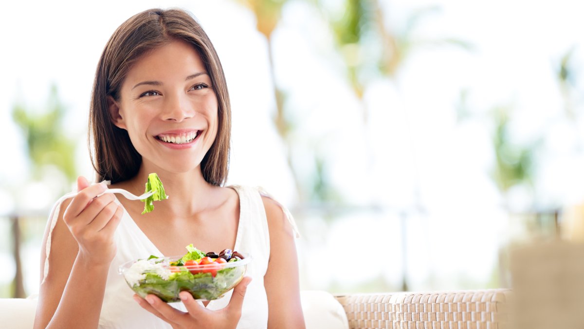 Glad kvinna äter sallad - Best Life-dieten handlar om livsstilsförändring